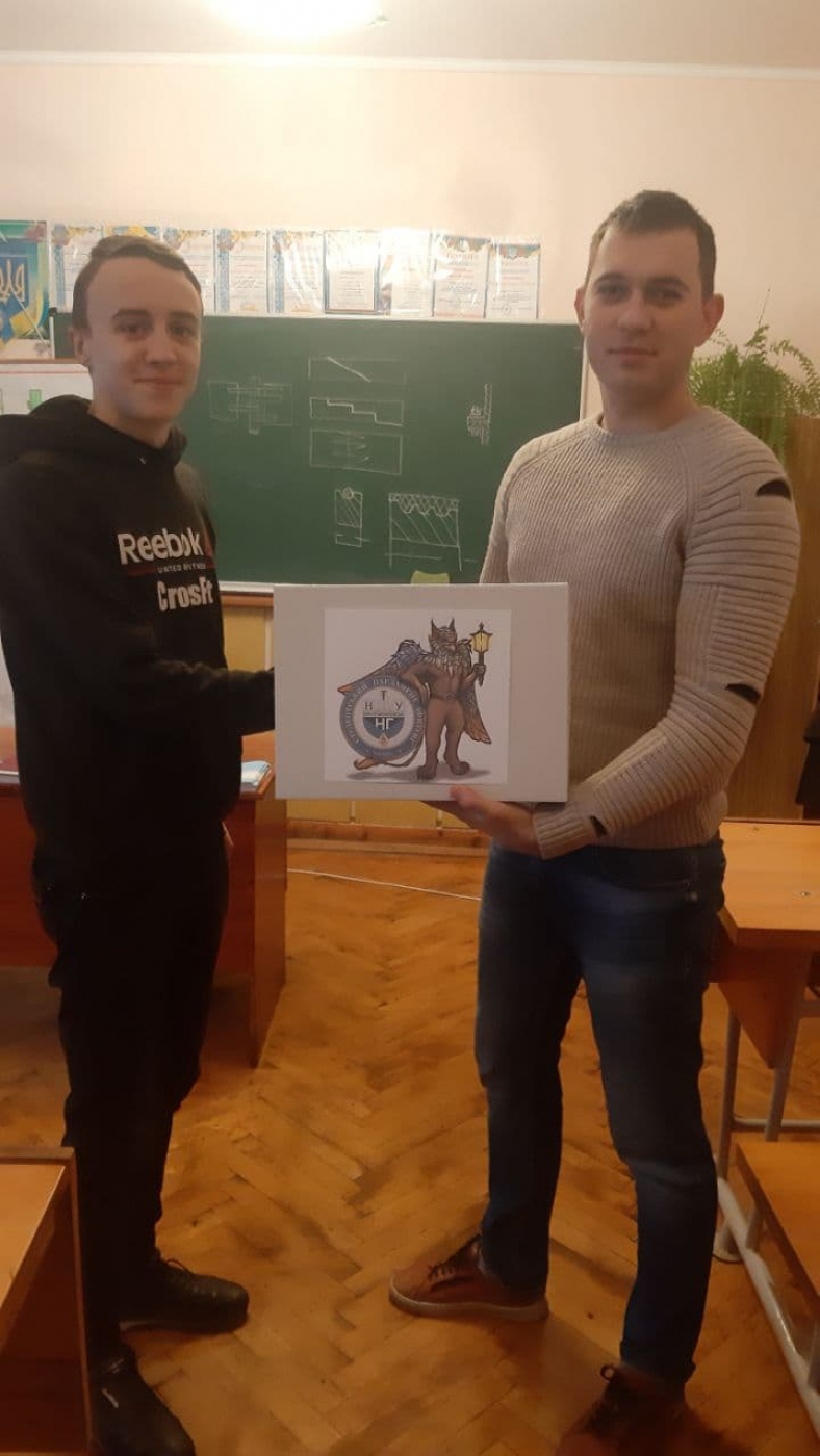 Викладач Калуського політехнічного коледжу Микола Романів передає своєму студенту Андрію Бураку настільну гру від Студентського парламенту ІФНТУНГ