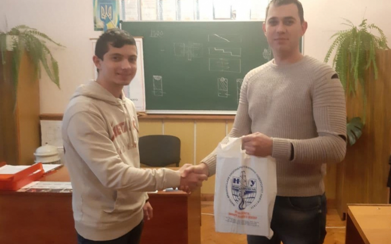 Викладач Калуського політехнічного коледжу  Микола Романів передає своєму студенту Богдану Цимбалістому подарунок від ІФНТУНГ